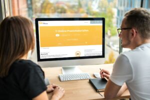 zwei Personen vor einem Monitor, auf dem die Online-Praxismaterialien-Datenbank des Forum Umweltbildung zu sehen ist